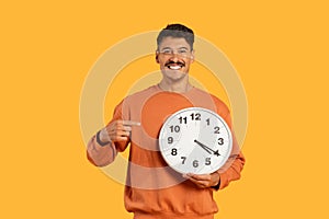 Happy guy with clock showing punctuality on yellow