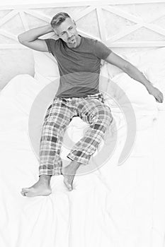 Happy guy in cozy pyjamas daydream resting in bed in morning, daydreaming