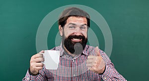 Happy guy drinking morning coffee from cup on green background, thumb up