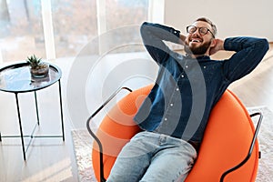 Happy Guy With Eyes Closed Relaxing Sitting In Chair Indoors