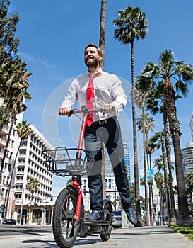 Happy guy in formalwear ride electric scooter on sidewalk, scooting photo