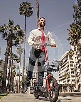 Happy guy in formalwear ride electric scooter on sidewalk, scooting