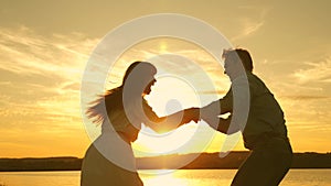 Happy guy and girl waltz in the evening in the summer park. Loving man and woman dance in bright rays of sun on the