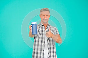 Happy guy give thumbs up hand gesture to mens gel bottle blue background copy space, approval