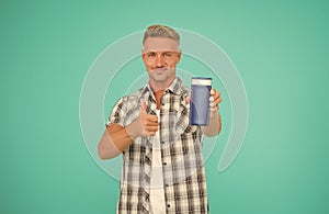 Happy guy give thumbs up hand gesture to mens gel bottle blue background copy space, approval