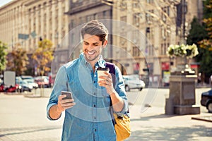Happy guy having walk in the city and typing sms photo