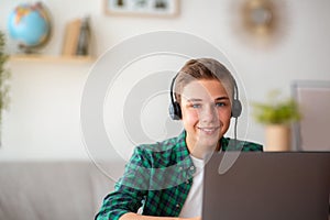 Happy guy in headset using laptop, spending time at home