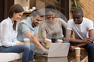 Happy guy showing diverse friends video on laptop outside coffeehouse