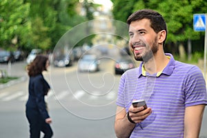 Happy guy with smartphone smiling messaging outdoors