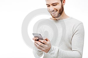 Happy guy typing message on the smartphone isolated. Handsome cheerful man using phone over white background