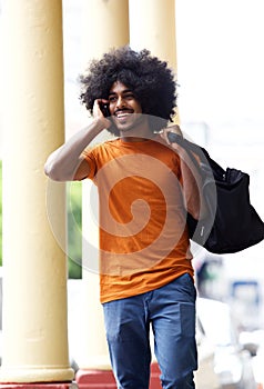 Happy guy walking in town with mobile phone and bag