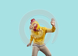Happy guy wearing funny yellow chicken mask dancing and having fun at crazy party