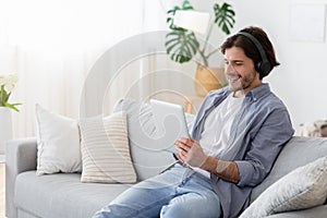 Happy guy with wireless headset and digital tablet at home