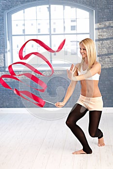 Happy gymnast girl exercising with ribbon