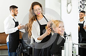 Happy hairdresser doing hairstyle