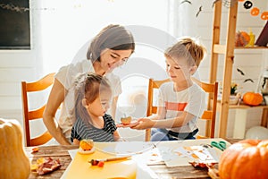 Happy Halloween. Attractive young woman with her little cute kids are preparing to Halloween on kitchen having fun with