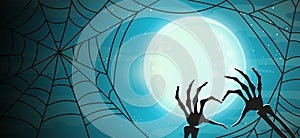 Happy Halloween banner background. Full moon on a background of dark sky, skeleton of hand bones showing heart symbol in