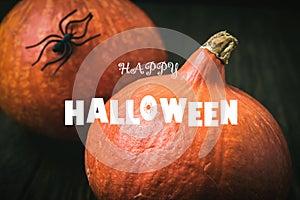 Happy Halloween banner. Pumpkins and black spider on dark table. Halloween typography on food background