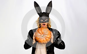 Happy Halloween. Beautiful woman in Halloween costume and bunny rabbit mask with pumpkin. Pretty female model in black