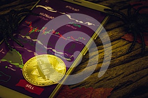 Happy Halloween BTC cryptocurrency Trading concept. Golden bitcoin on smartphone with spooky btc trading application photo