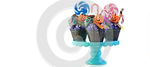 Halloween candyland drip cake style cupcakes with lollipops and candy on white.