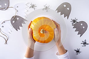 Happy halloween. Child hand holding little pumpkin. Funny handmade paper ghost, spiders toy on white background. Concept DIY and