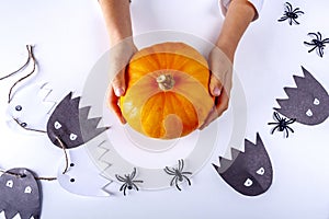 Happy halloween. Child hand holding little pumpkin. Funny handmade paper ghost, spiders toy on white background. Concept DIY and