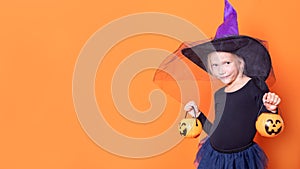 Happy Halloween. Children are celebrating Halloween. Joyful girl in a witch costume holding a bucket of sweets in the