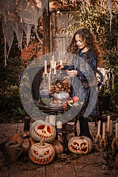 Happy Halloween Concept! Cute little witch cooking a potion in the decorated garden.