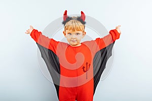 Happy Halloween! Cute little boy in devil halloween costume with horns on light blue background