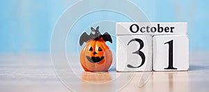 Happy Halloween day with 31 October calendar wood, jack o lantern pumpkin and bat decor with funny face on table background with