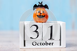 Happy Halloween day with 31 October calendar wood, jack o lantern pumpkin and bat decor with funny face on table background with