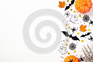 Happy Halloween flat lay composition with pumpkins, bats, ghosts, skeleton arms, spiders, webs. Top view, copy space. Halloween