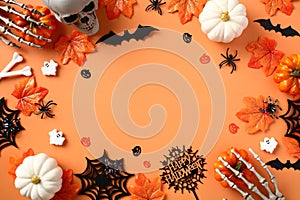 Happy Halloween flat lay composition with spooky skull, bats, spiders, webs, pumpkins, skeleton hands on orange background