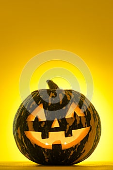 Happy Halloween. Funny glowing pumpkin Jack-o-lantern on a yellow background.