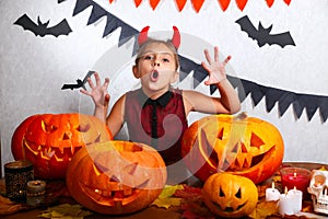 Happy halloween. Funny little child girl with carving pumpkin. Happy family preparing for Halloween.