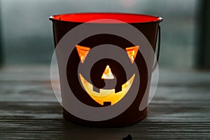 Happy Halloween. Glowing Jack-o-lantern face in dark. Spooky atmospheric jack o lantern glowing pumpkin bucket on black background