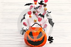 Happy Halloween. Halloween candy spilled from jack o lantern bucket with skulls, black bats, ghost, spider decorations on white