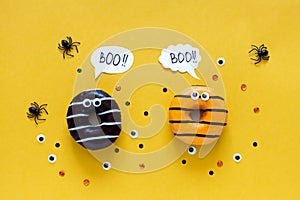 Happy halloween holiday concept. Funny food for kids - scared donuts bright yellow background with black spider and eyes