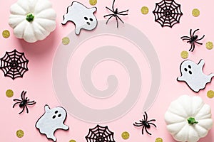 Happy Halloween holiday concept. Halloween decorations, pumpkins, spiders, webs, ghosts, confetti on pastel pink background