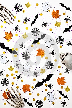 Happy Halloween holiday concept. Pattern made of Halloween decorations, bats, skeleton hands, ghosts, spiders, webs on white