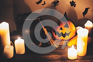 Happy Halloween. Jack o lantern pumpkin with candles, bowl, witch broom and bats, ghosts on background in dark spooky room. fall