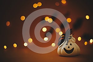 Happy Halloween. Jack o lantern pumpkin with spider decoration on dark orange background with magical lights and flying black bats