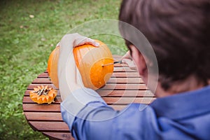 Happy halloween. Man carving big pumpkin Jack O Lanterns for Halloween outside. Close-up