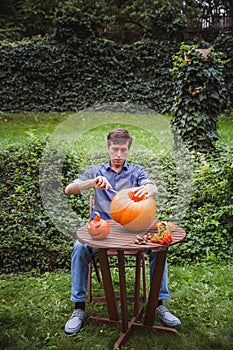 Happy halloween. Man carving big pumpkin Jack O Lanterns for Halloween outside. Close-up