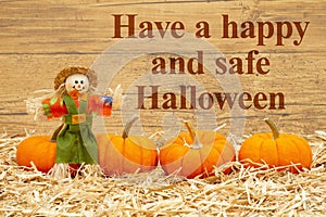 Happy Halloween message with scarecrow and orange pumpkins on straw hay