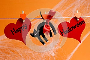 Happy Halloween message written across red hearts and black cat with pegs hanging from a line