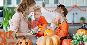 Happy Halloween! mother treats children with candy at home