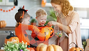 Happy Halloween! mother treats children with candy at home