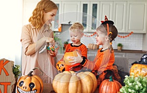 Happy Halloween! mother treats children with candy at home